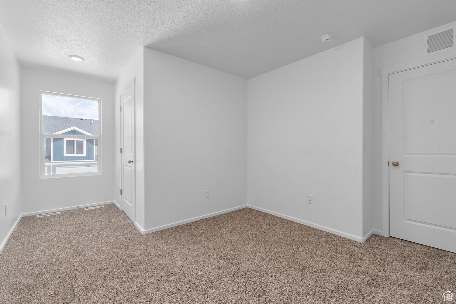 Secondary bedroom with light colored carpet and a textured ceiling