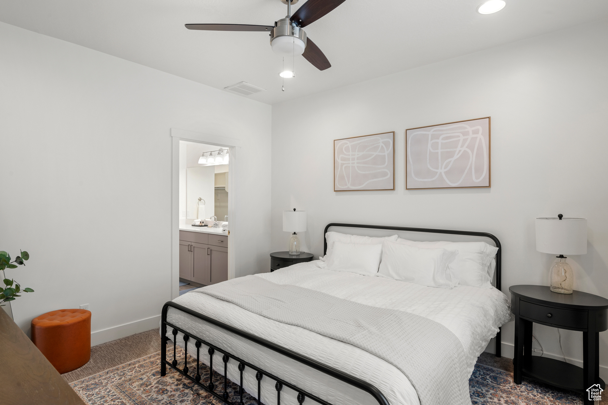 Bedroom featuring ceiling fan, dark carpet, and ensuite bath