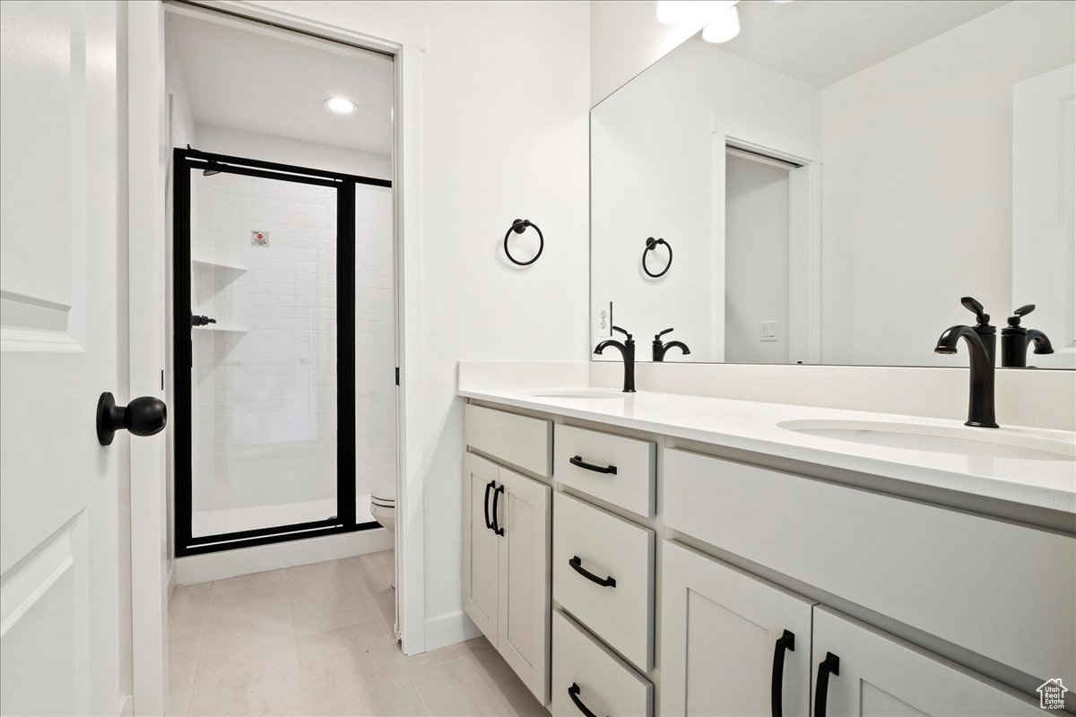 Bathroom featuring tile patterned floors, vanity, a shower with shower door, and toilet