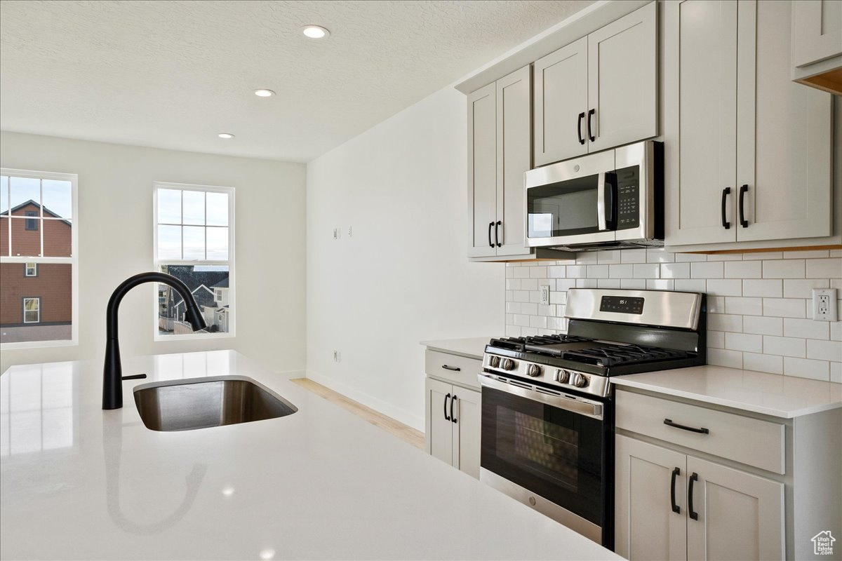 Kitchen with backsplash, sink, and stainless steel appliances