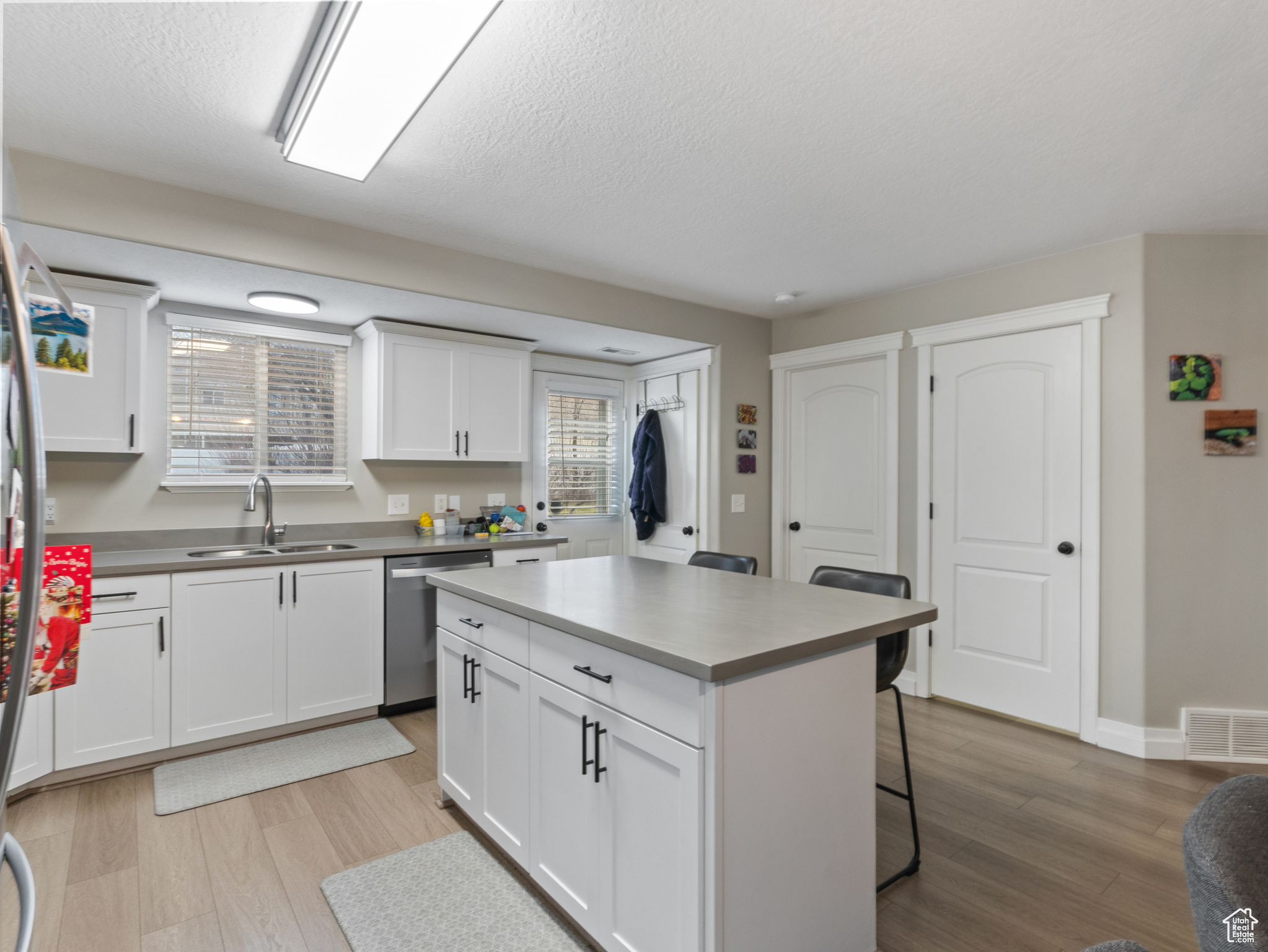 Kitchen with sink, dishwasher, a center island, white cabinetry, and a breakfast bar area