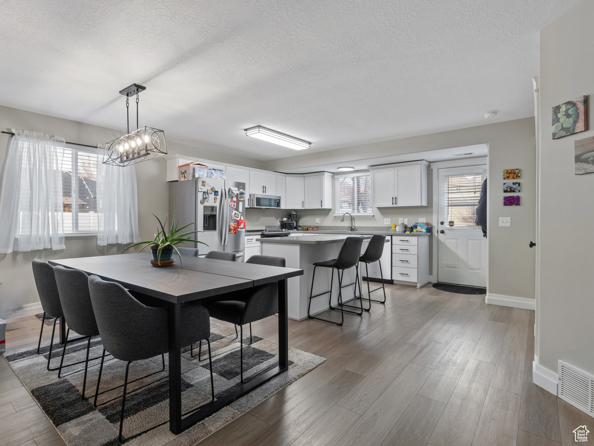 Dining room featuring light wood-type flooring, a textured ceiling, and sink