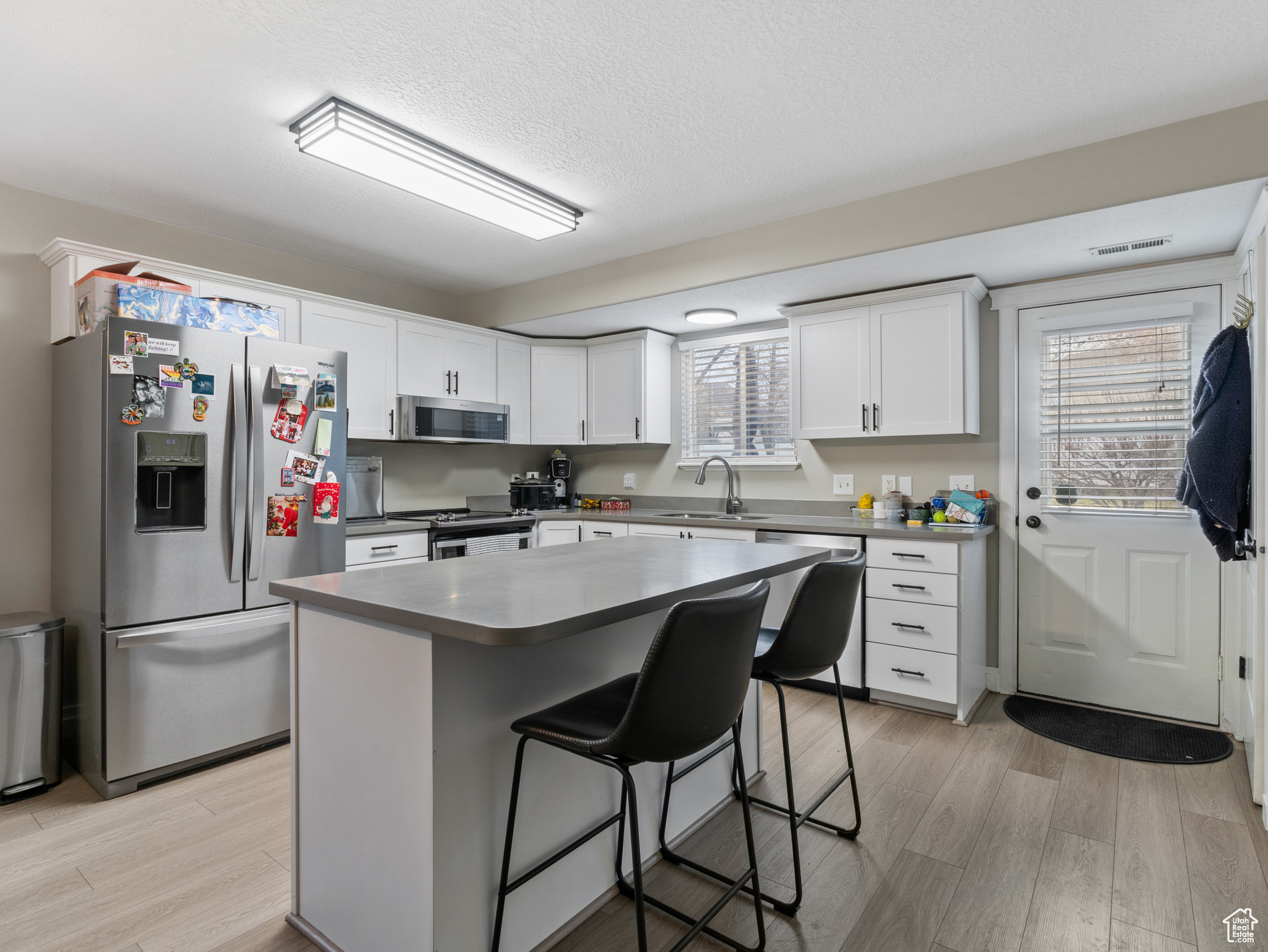 Kitchen with white cabinetry, a center island, sink, stainless steel appliances, and a kitchen breakfast bar