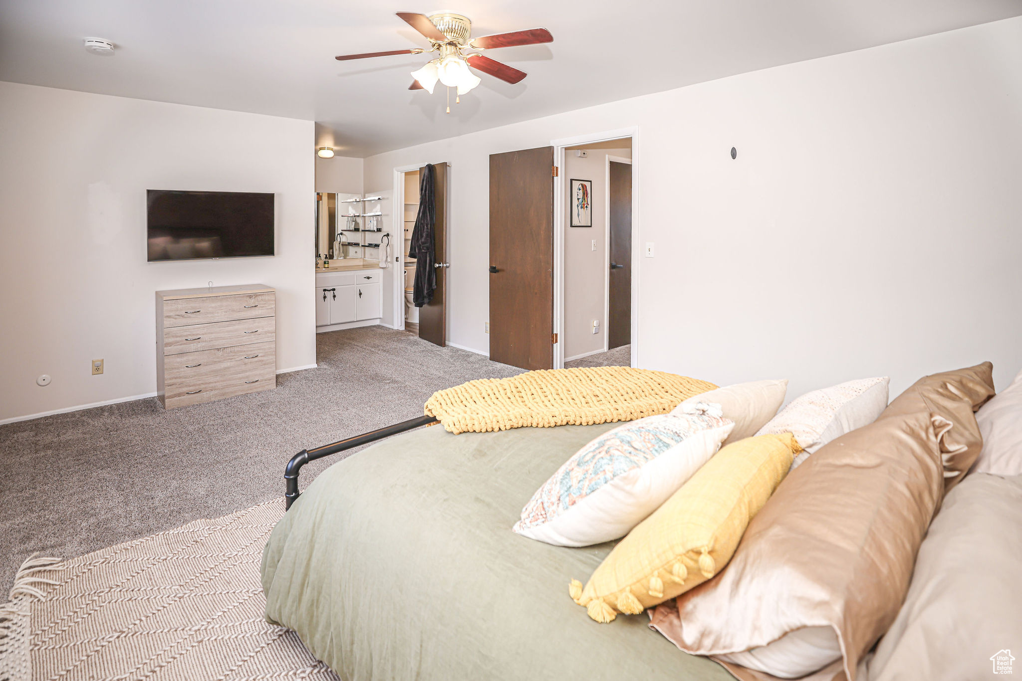 Carpeted bedroom featuring connected bathroom and ceiling fan