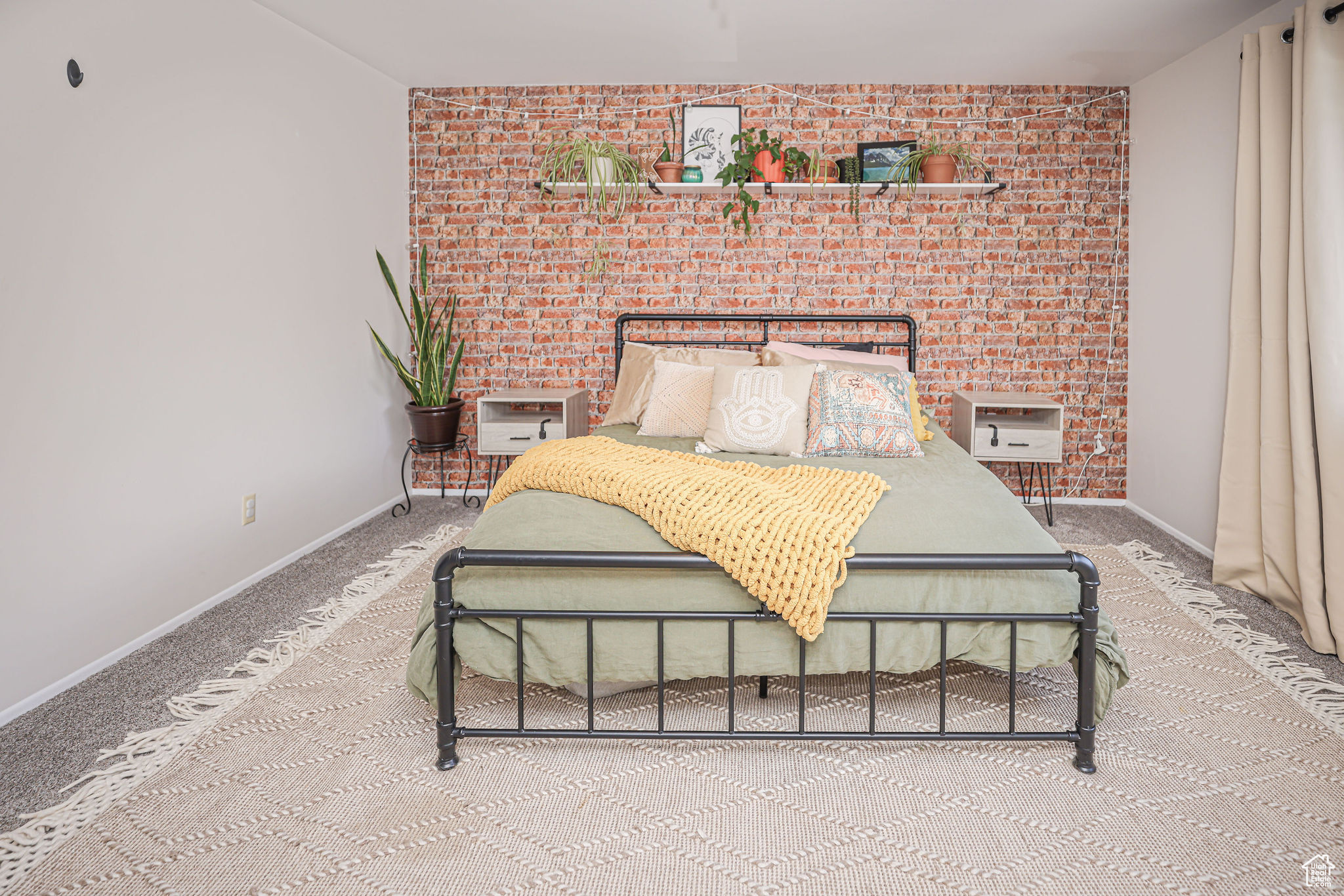 Carpeted bedroom featuring brick wall