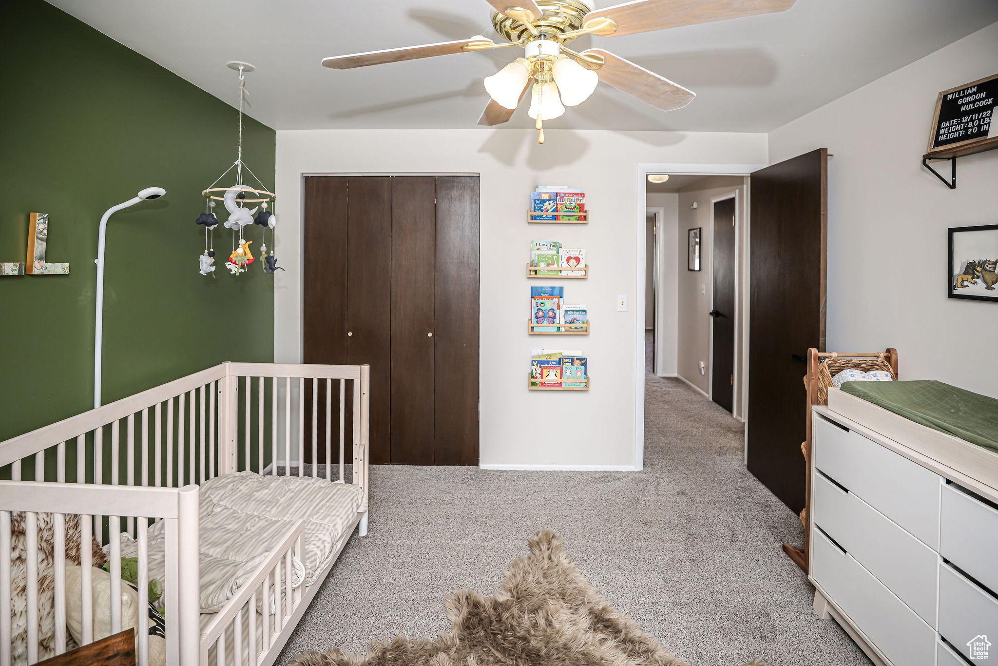 Bedroom with a crib, carpet flooring, a closet, and ceiling fan