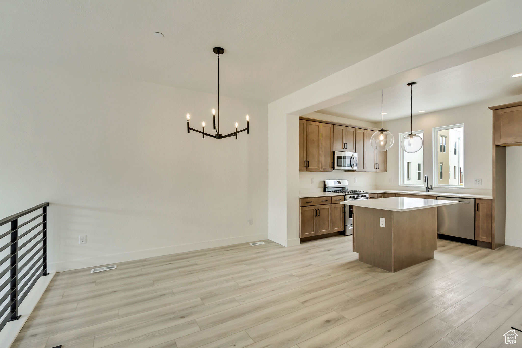 Kitchen with stainless steel appliances, an inviting chandelier, light hardwood / wood-style flooring, a center island, and hanging light fixtures