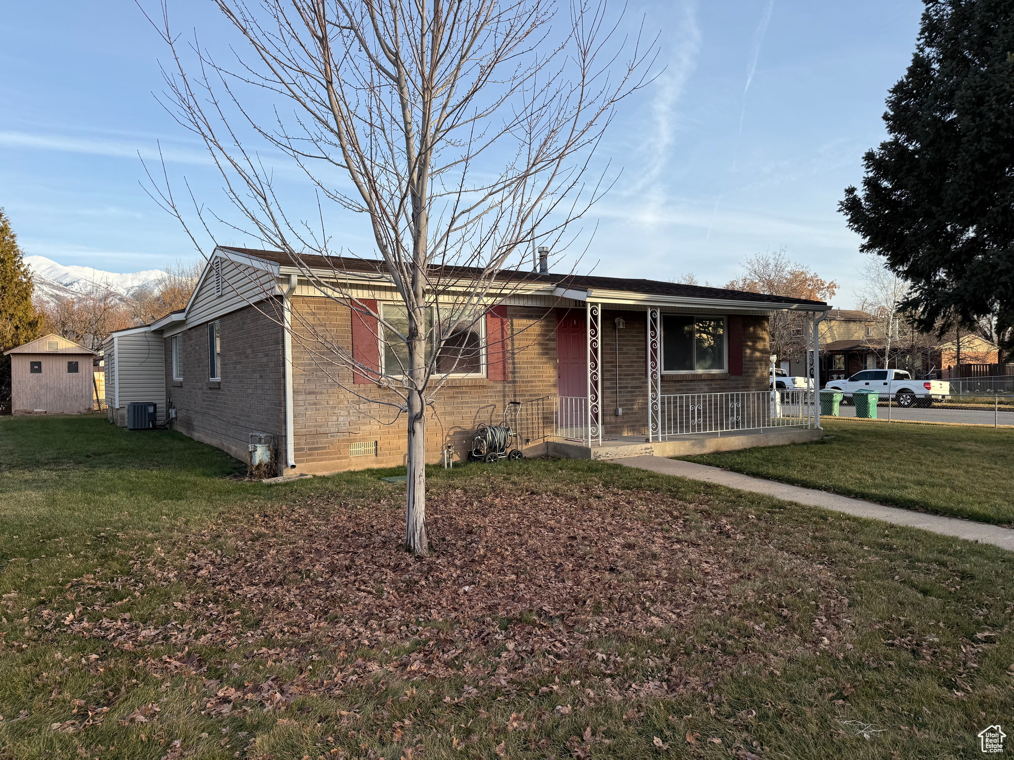 View of front facade with central air condition unit, covered porch, and a front yard