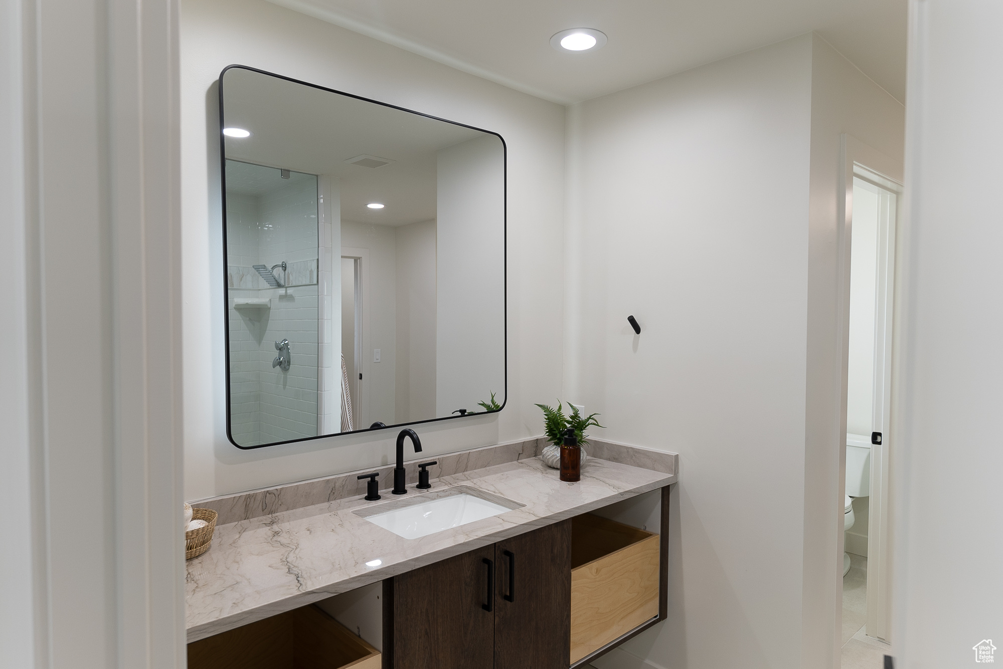 Bathroom featuring a tile shower, vanity, and toilet