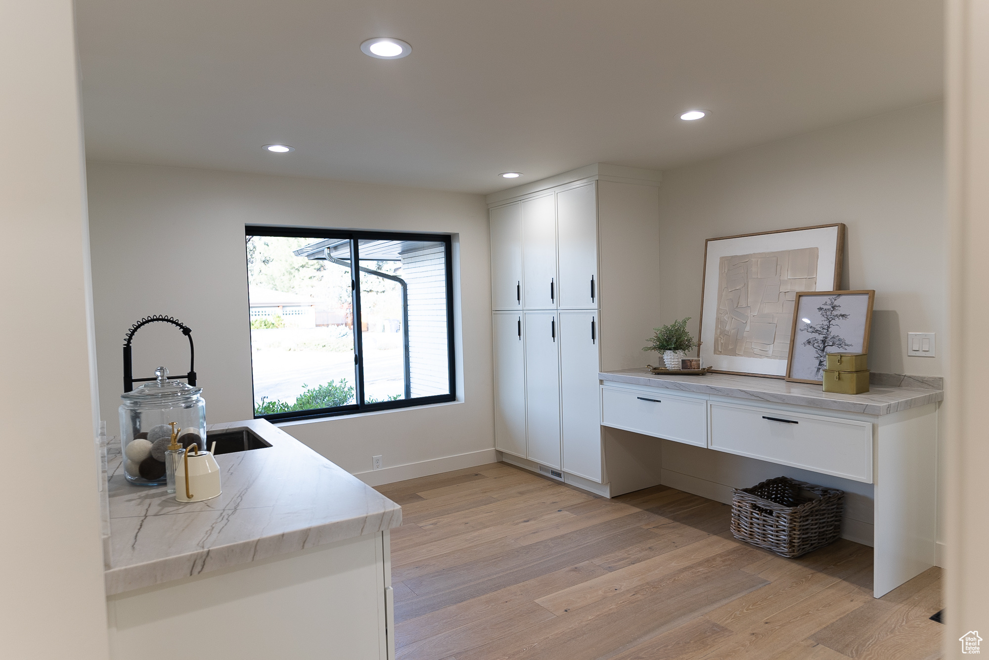 Interior space with white cabinets, kitchen peninsula, sink, and light hardwood / wood-style flooring