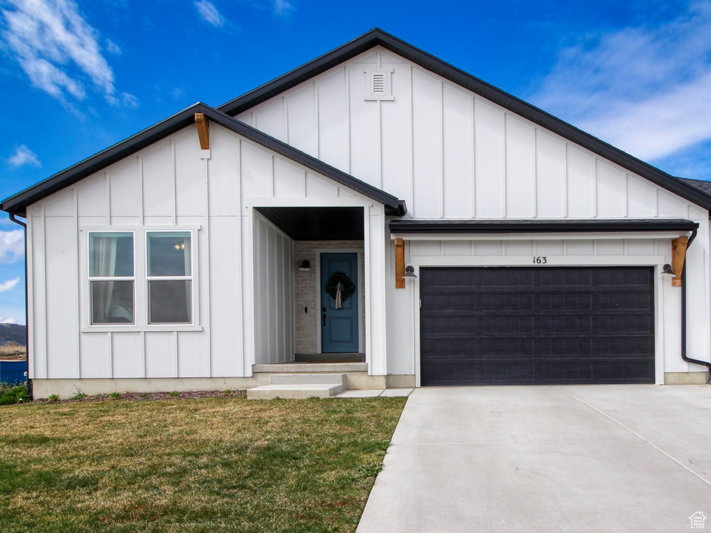 Modern inspired farmhouse featuring a garage and a front yard