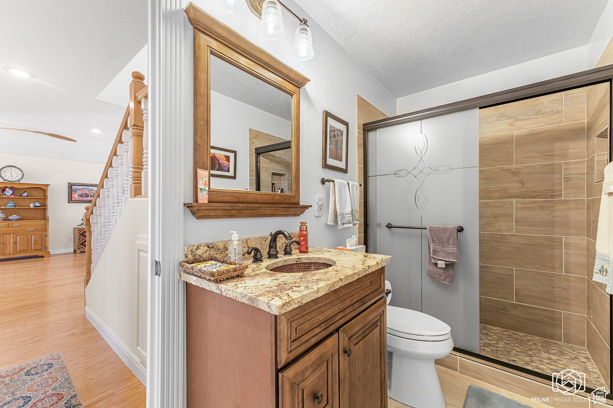 Bathroom with hardwood / wood-style floors, a textured ceiling, toilet, a shower with door, and vanity