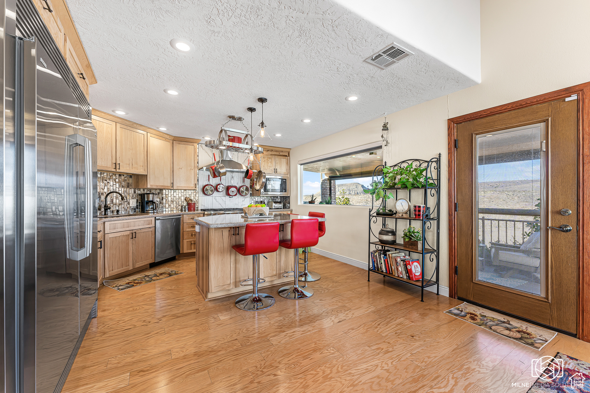 Kitchen with a breakfast bar, a center island, hanging light fixtures, built in appliances, and decorative backsplash