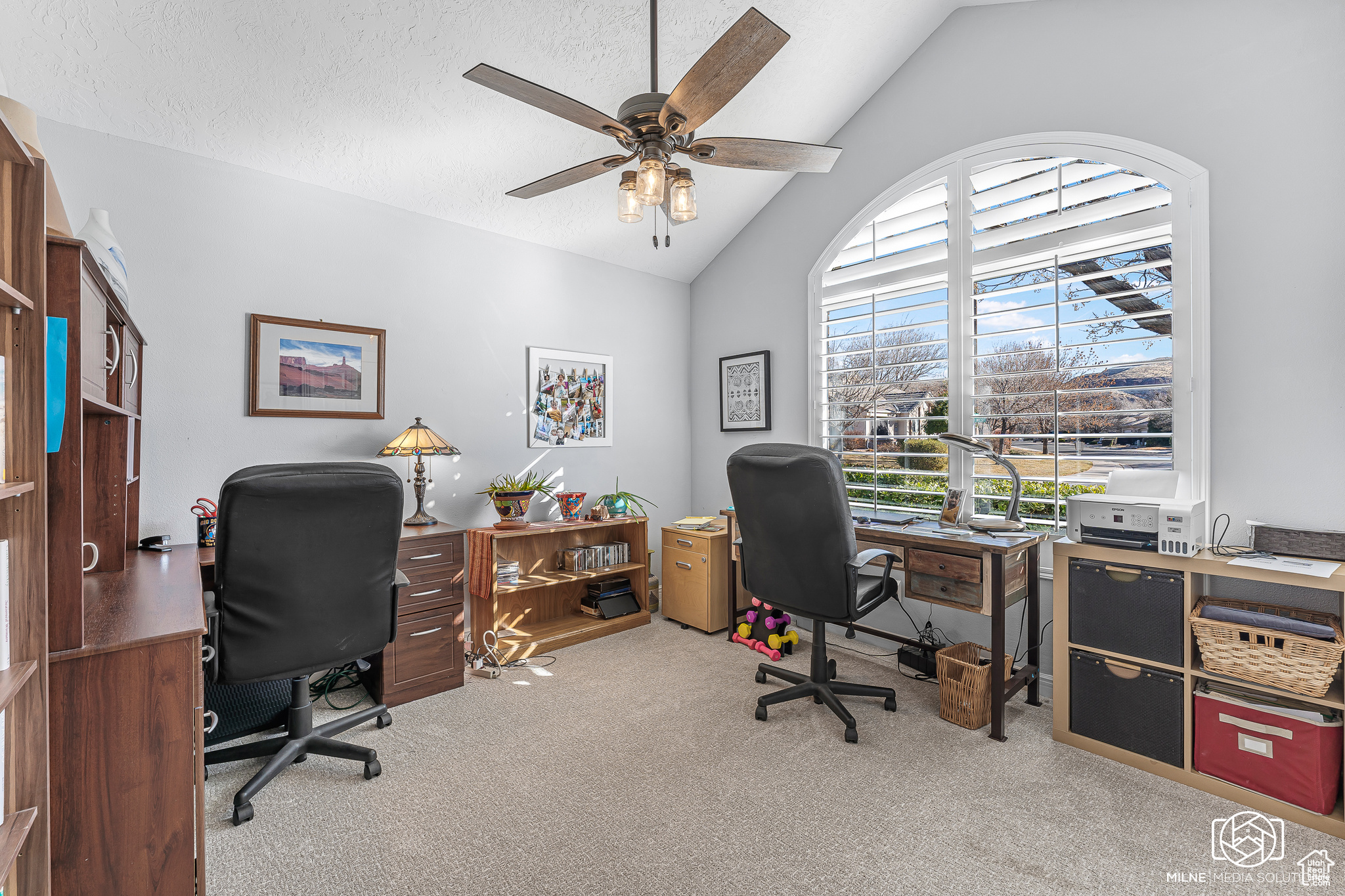 Office space with a textured ceiling, ceiling fan, light carpet, and lofted ceiling