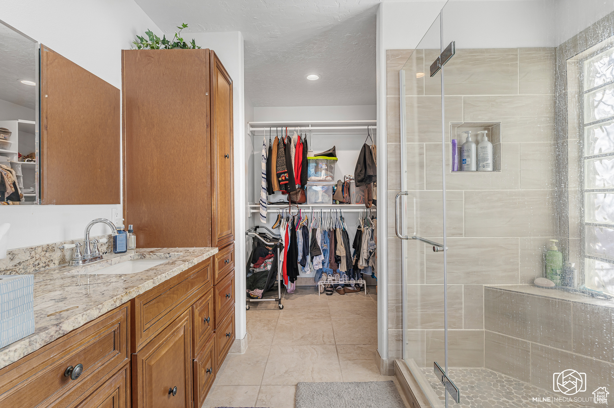 Bathroom with tile patterned floors, vanity, a shower with shower door, and a textured ceiling