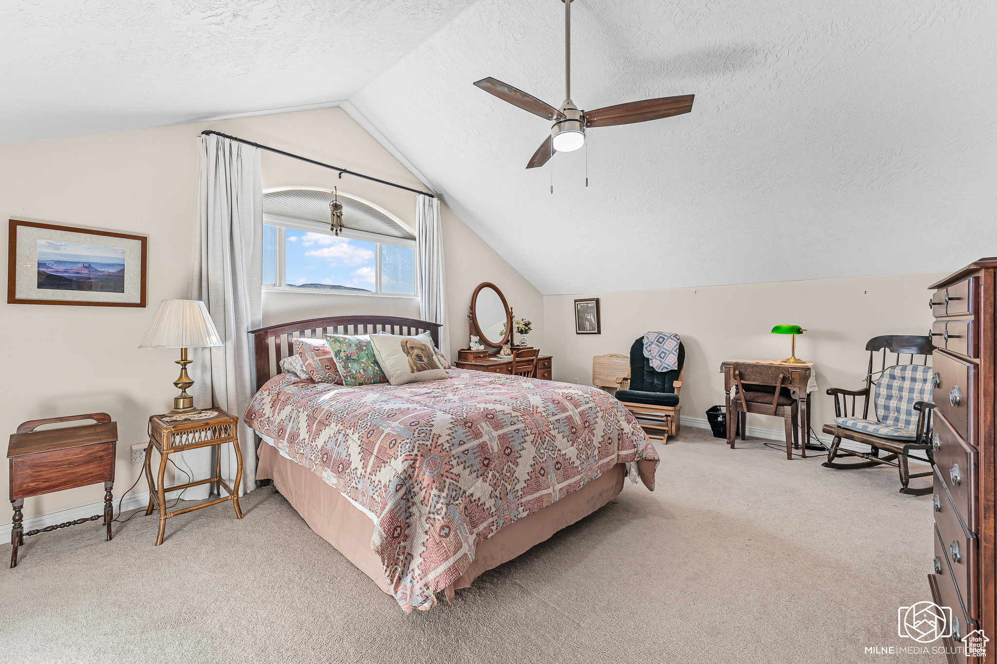 Carpeted bedroom featuring vaulted ceiling, ceiling fan, and a textured ceiling