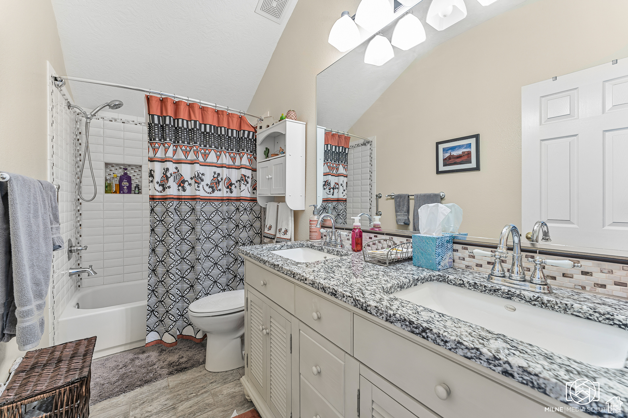 Full bathroom featuring hardwood / wood-style floors, vanity, lofted ceiling, toilet, and shower / bathtub combination with curtain