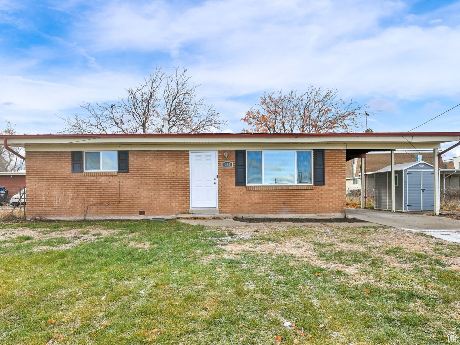 View of front of property featuring a storage unit and a front lawn