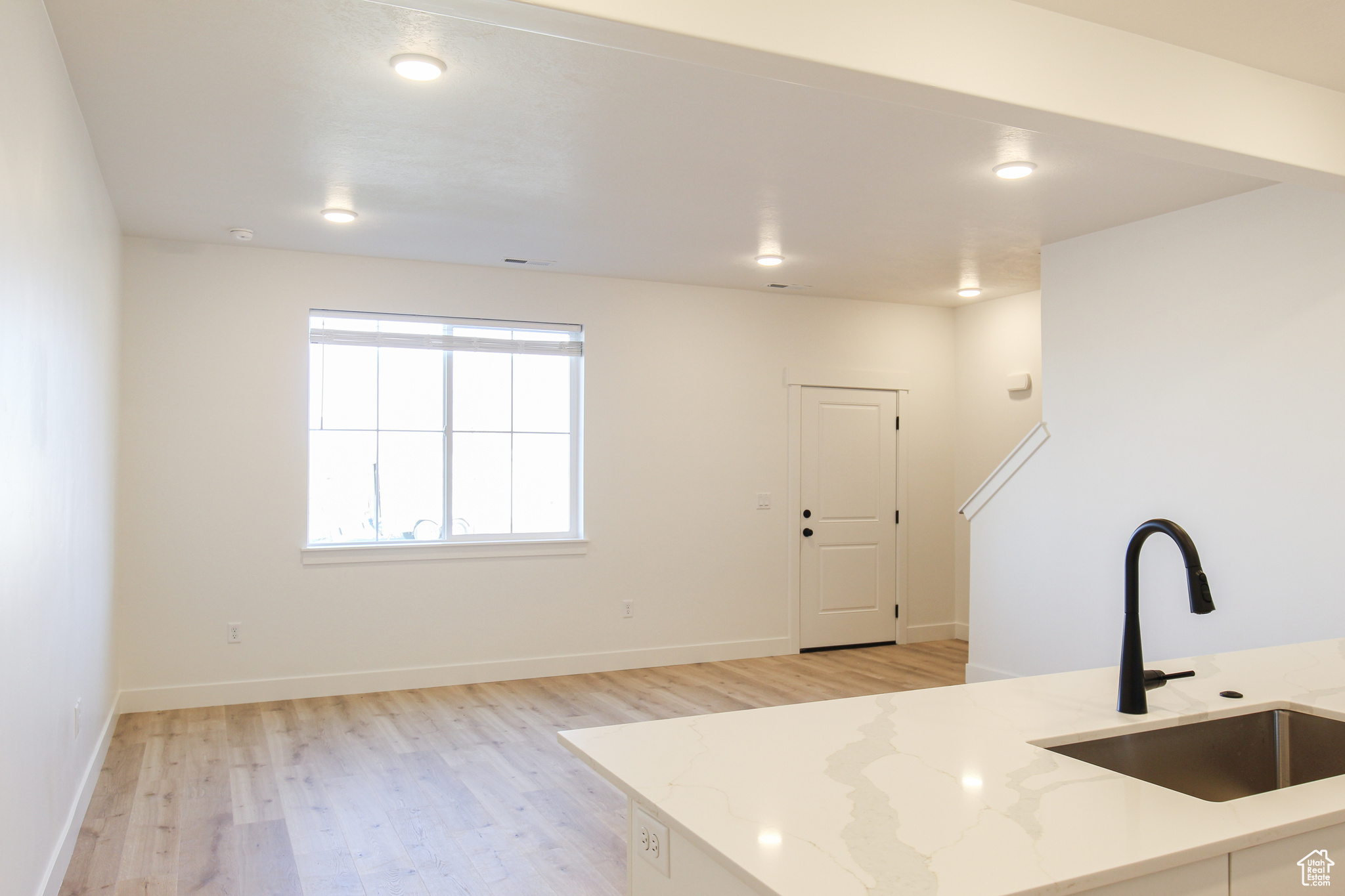 Kitchen featuring light stone counters, light wood-type flooring, and sink