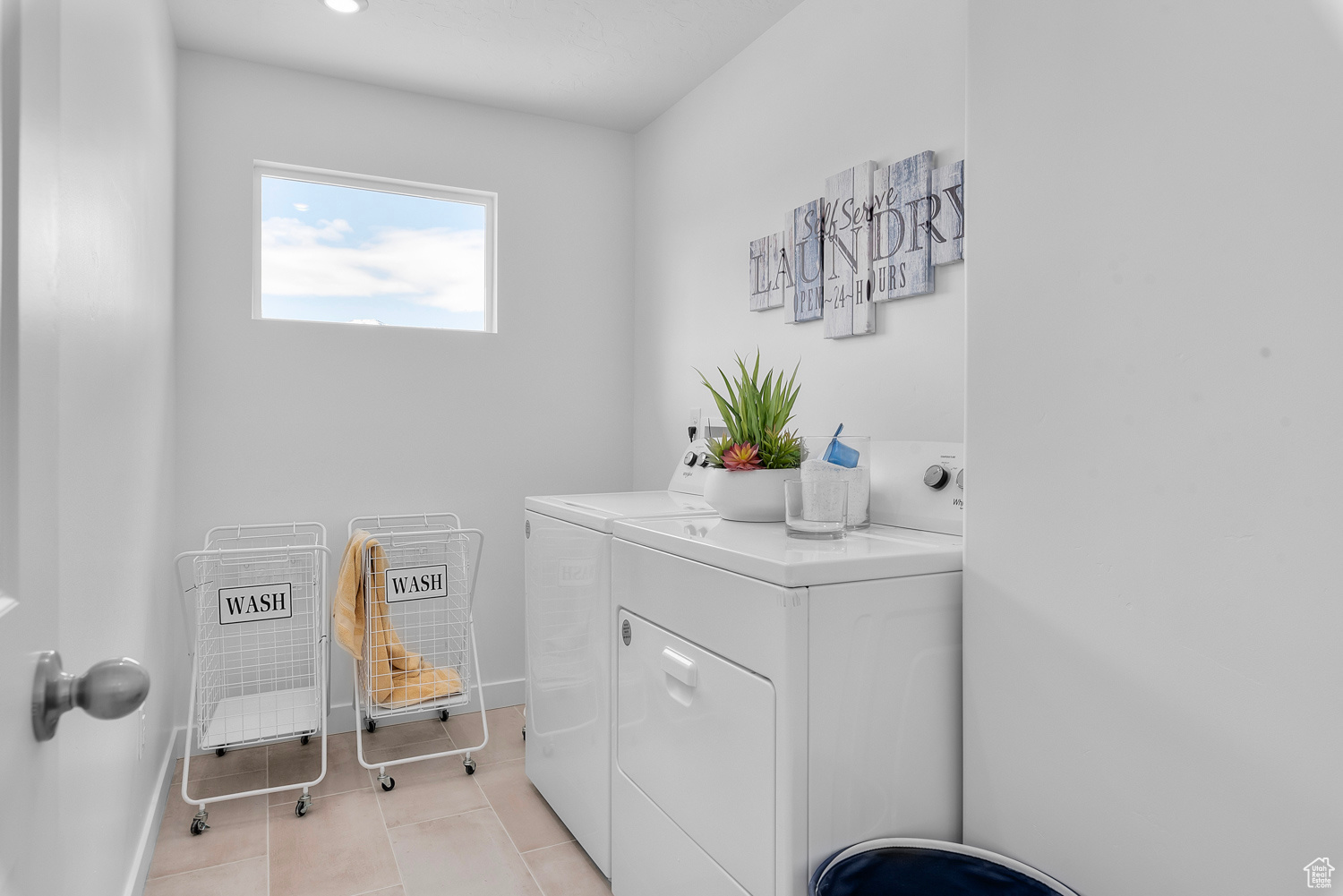 Clothes washing area with light tile patterned flooring and independent washer and dryer