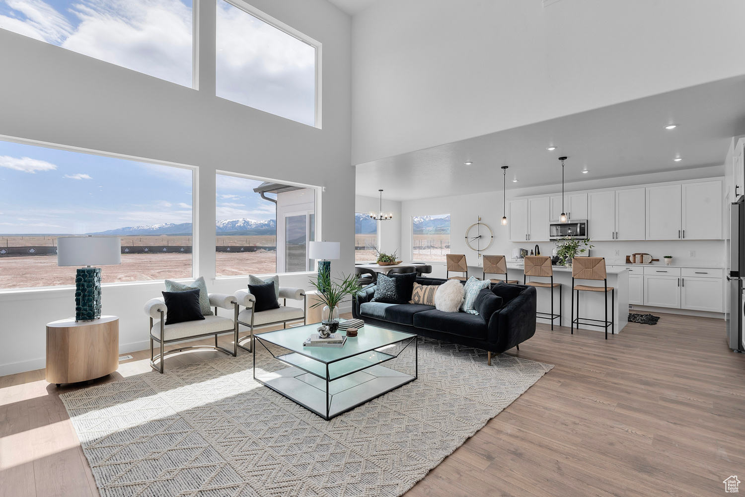 Living room with a mountain view, a high ceiling, light hardwood / wood-style flooring, and a notable chandelier