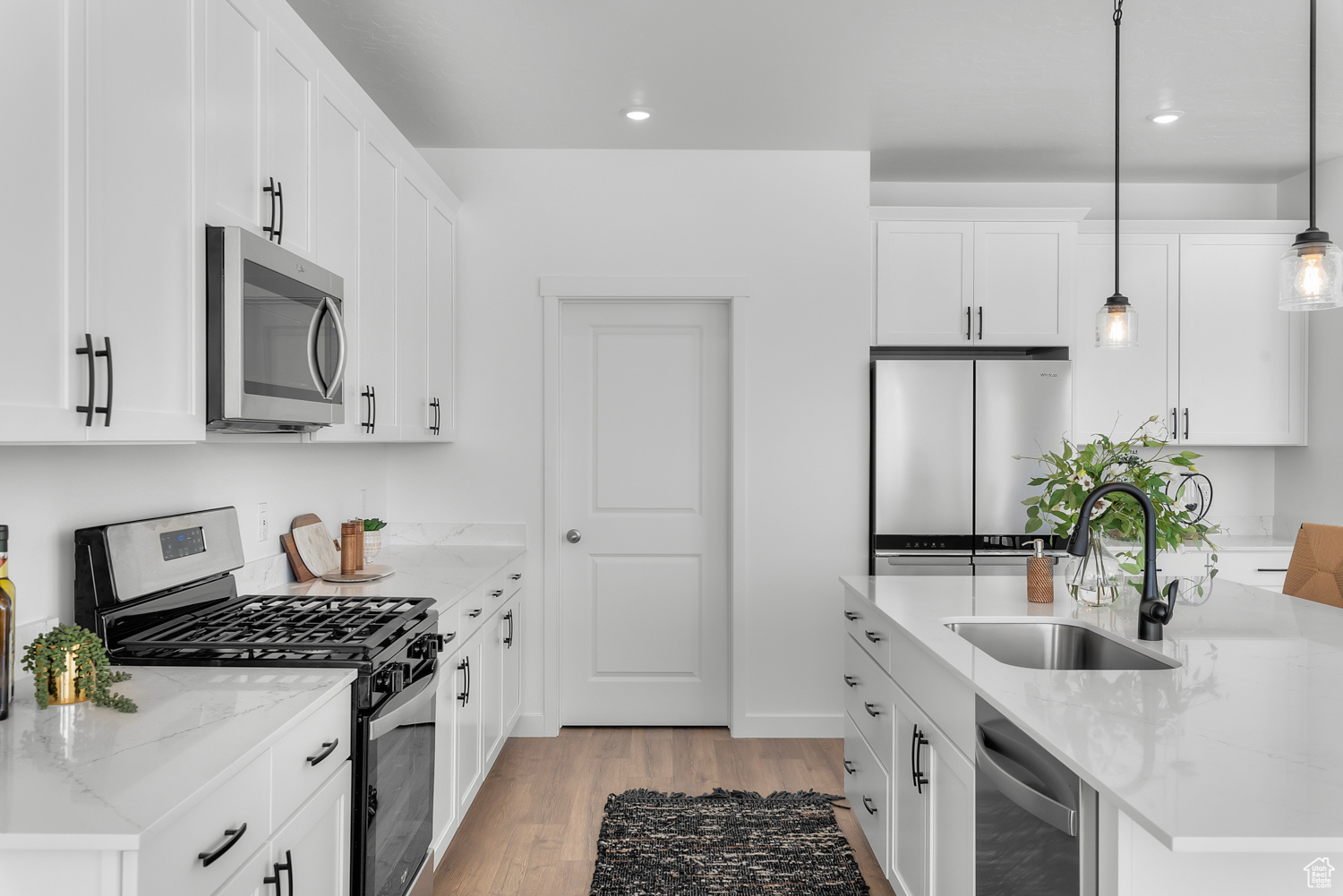 Kitchen featuring pendant lighting, sink, white cabinetry, and stainless steel appliances