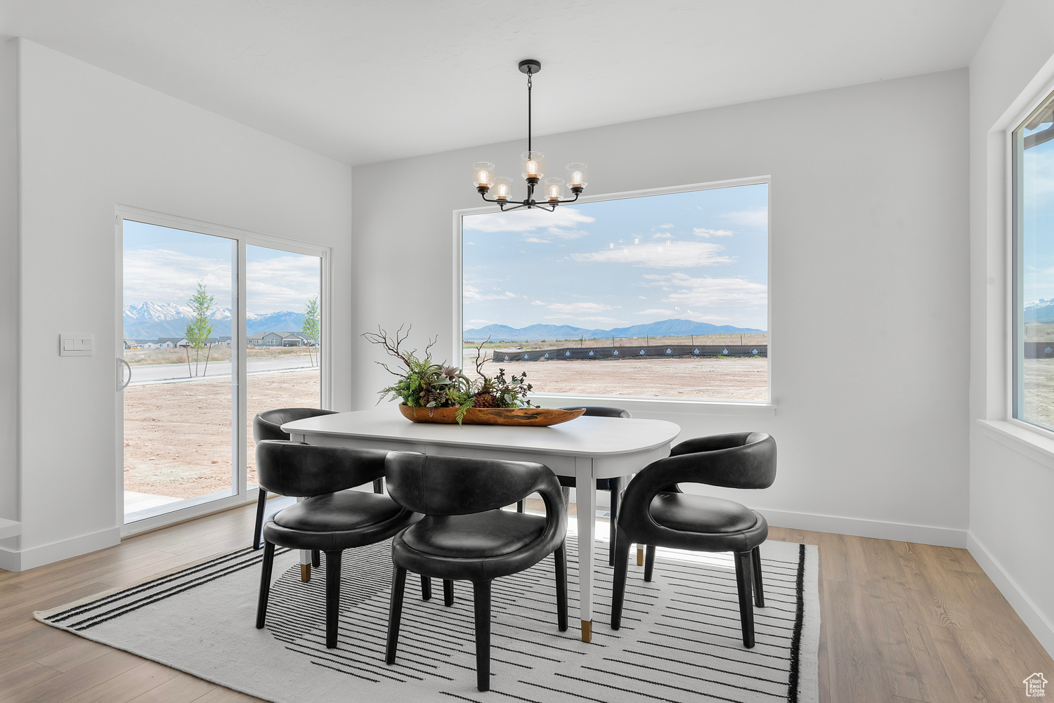 Dining room featuring a wealth of natural light, light wood-type flooring, a water and mountain view, and a chandelier