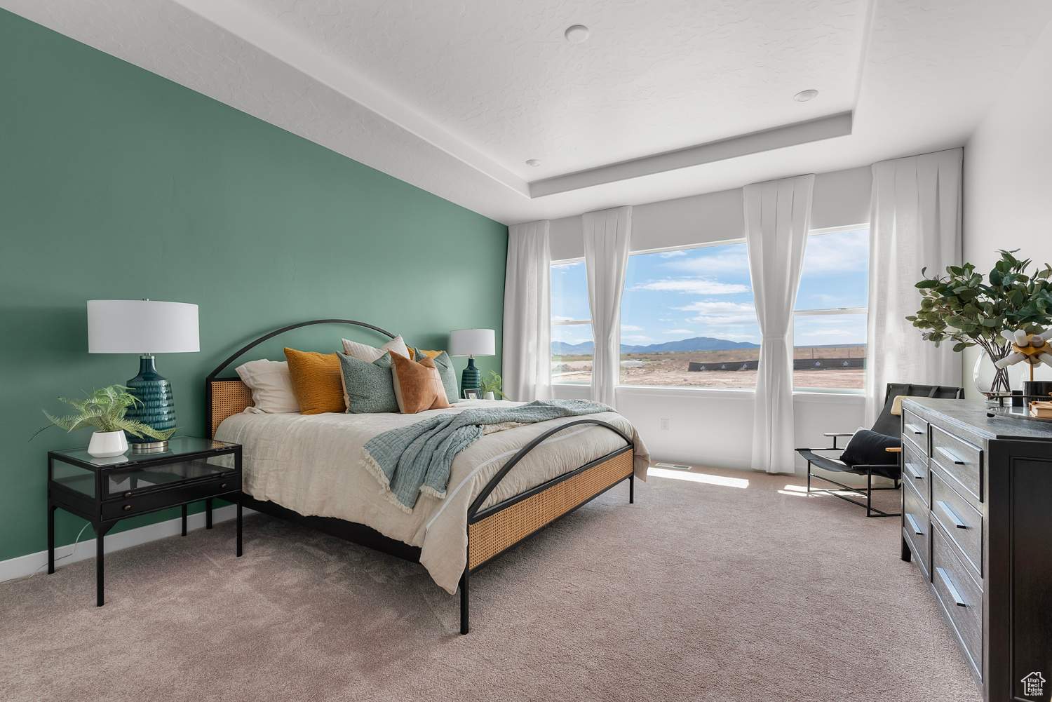 Bedroom with a raised ceiling and light carpet