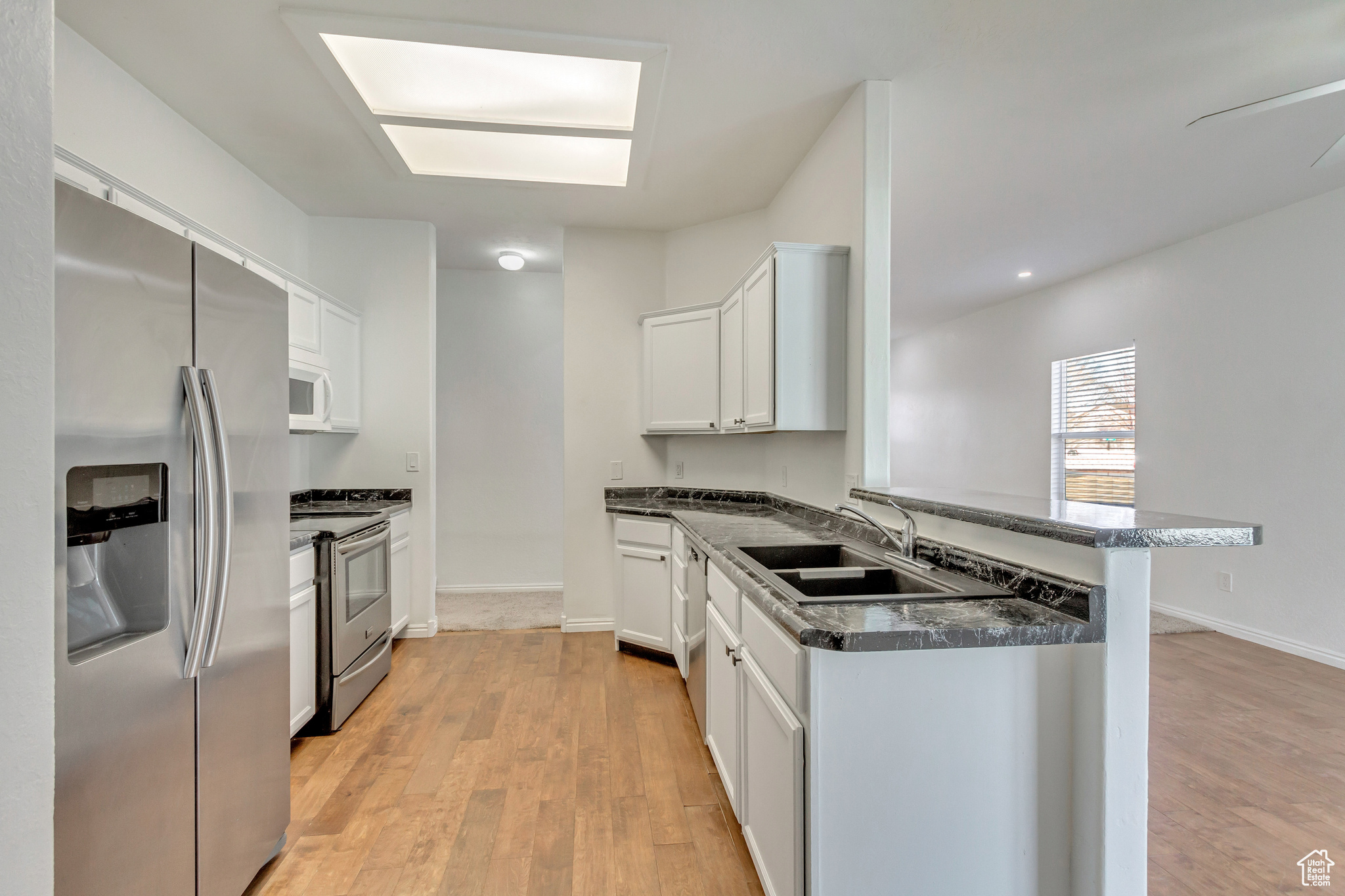 Kitchen featuring kitchen peninsula, sink, white cabinets, and stainless steel appliances