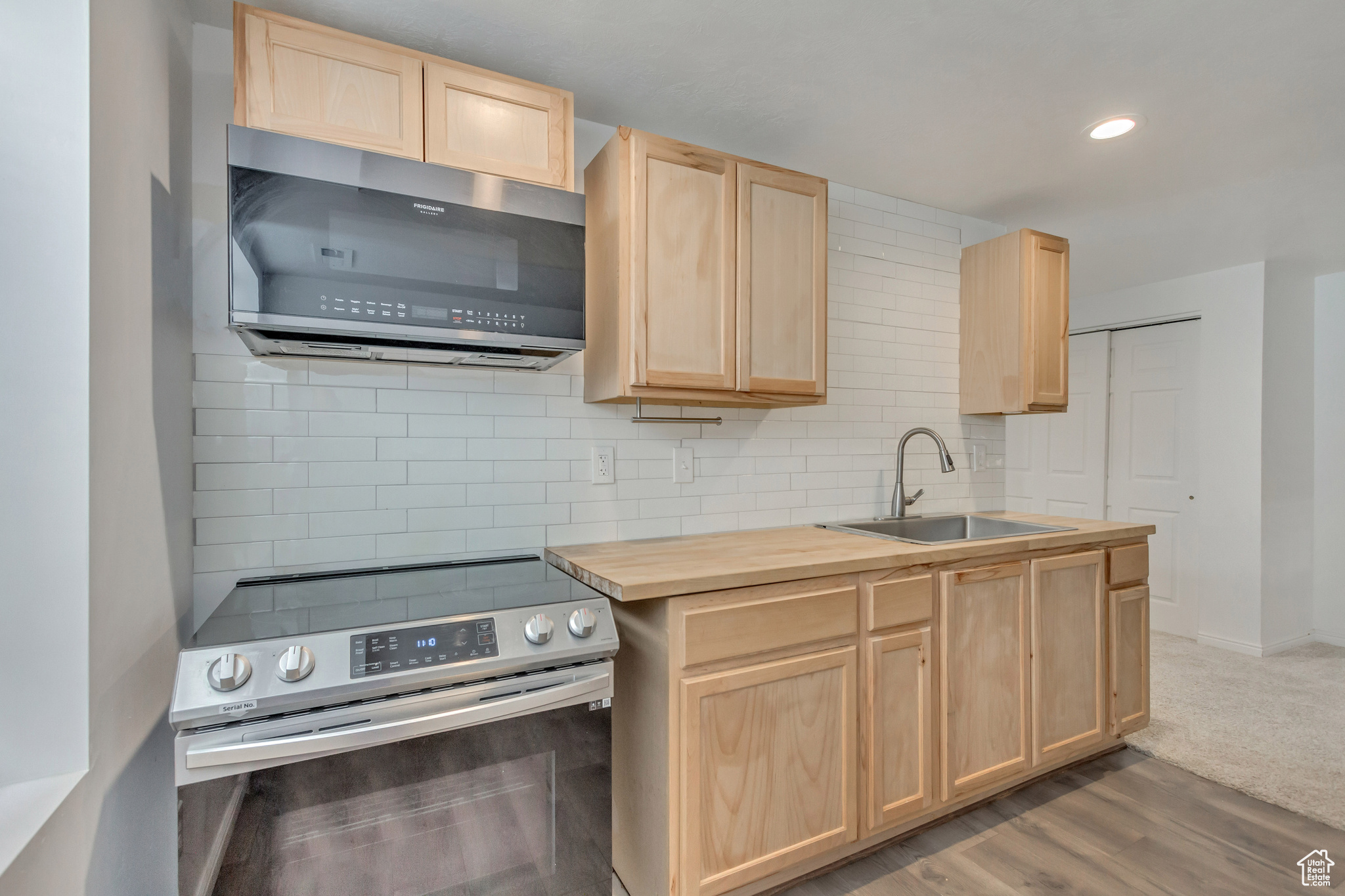 Basement Kitchen with wood counters, light brown cabinetry, stainless steel appliances, sink, and dark hardwood / wood-style floors