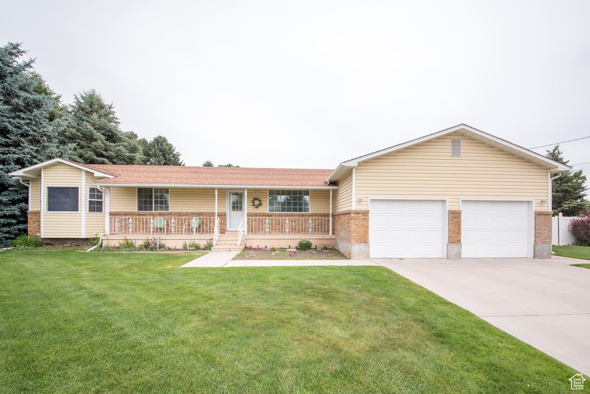 Single story home featuring a porch, a garage, and a front yard