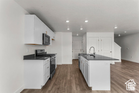 Kitchen featuring white cabinetry, sink, and stainless steel stove