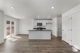 Kitchen with dark hardwood / wood-style flooring, white cabinetry, a center island with sink, and sink