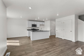 Kitchen with white cabinets, a center island with sink, and dark hardwood / wood-style floors