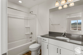 Full bathroom featuring toilet, vanity, wood-type flooring, and tub / shower combination