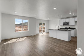 Kitchen featuring white cabinets, sink, a center island with sink, and dark wood-type flooring