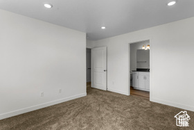 Unfurnished bedroom with dark colored carpet and ensuite bath