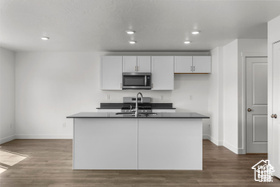 Kitchen featuring white cabinetry, sink, a kitchen island with sink, and dark hardwood / wood-style floors