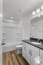 Full bathroom featuring toilet, hardwood / wood-style floors, vanity, and washtub / shower combination