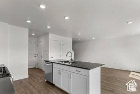 Kitchen featuring sink, dark hardwood / wood-style floors, a center island with sink, white cabinets, and appliances with stainless steel finishes