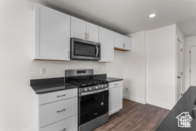 Kitchen featuring white cabinets, appliances with stainless steel finishes, and dark wood-type flooring