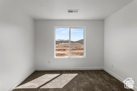 Empty room featuring dark colored carpet