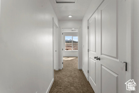 Hall featuring dark colored carpet