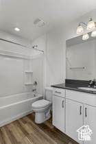 Full bathroom featuring vanity, shower / bath combination, toilet, and hardwood / wood-style flooring