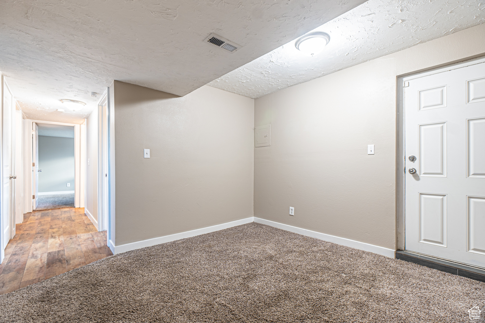 Unfurnished room with a textured ceiling and carpet floors