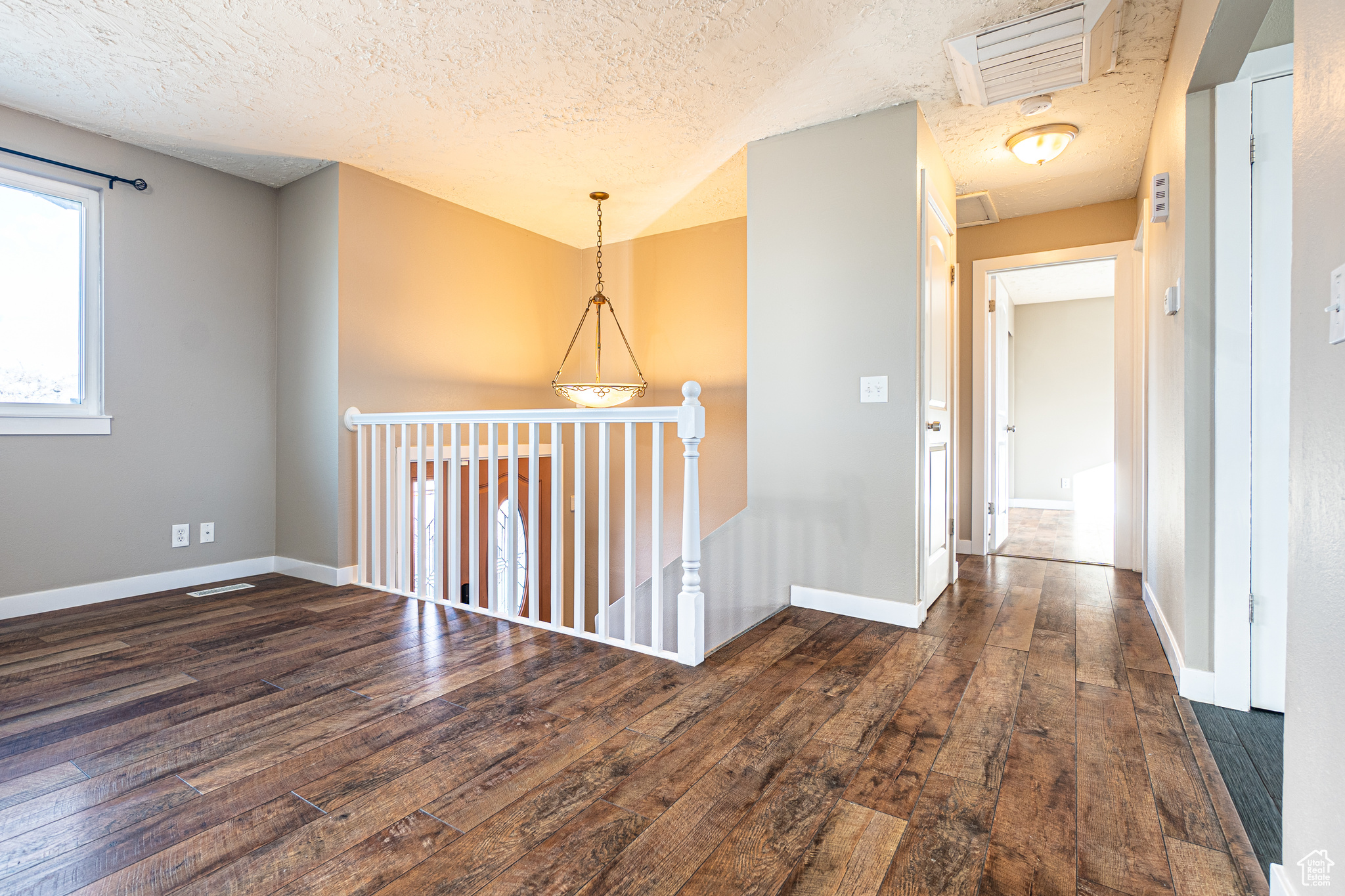 Hallway featuring a textured ceiling and dark hardwood / wood-style flooring