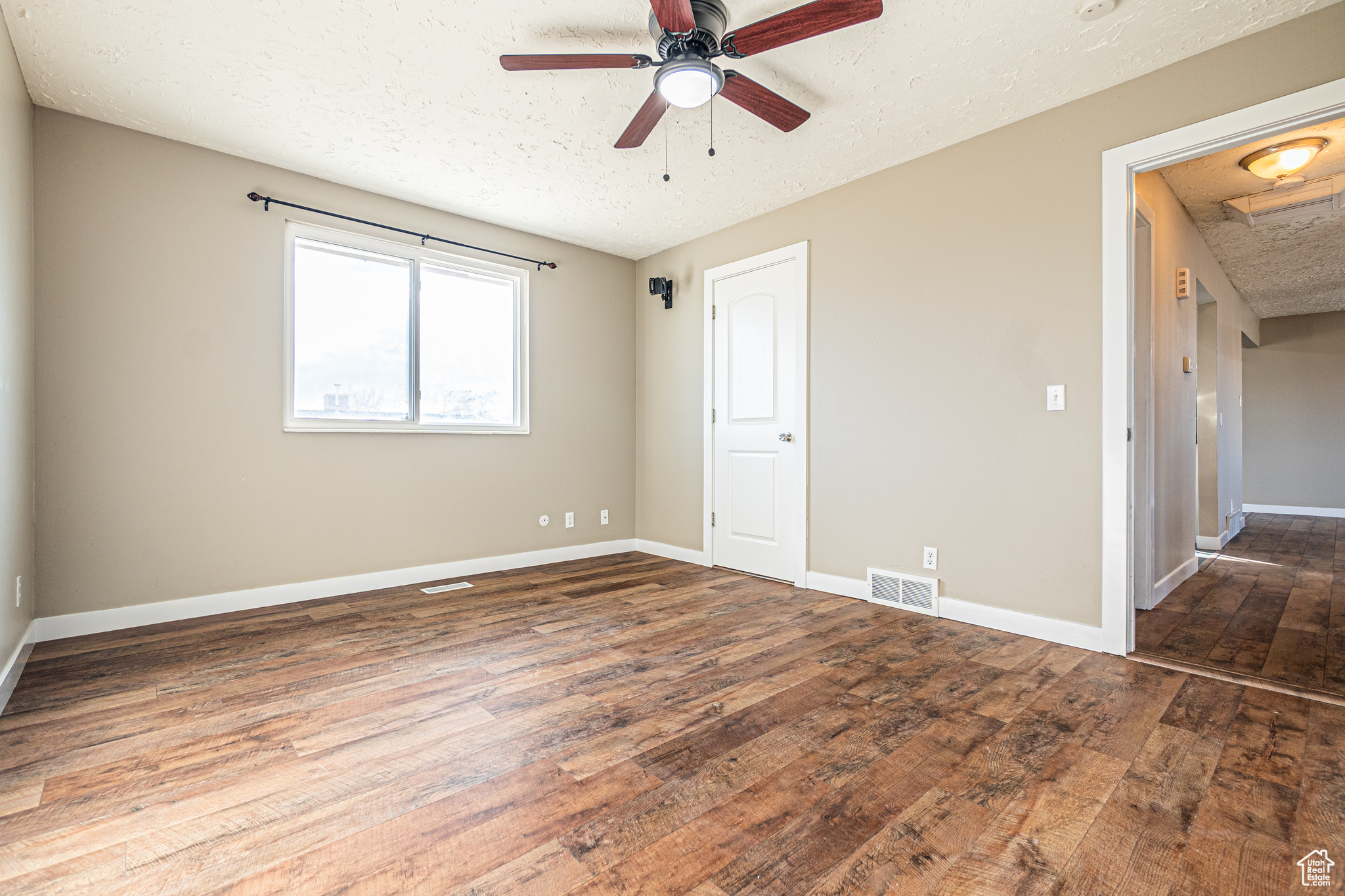 Spare room featuring a textured ceiling, dark hardwood / wood-style floors, and ceiling fan