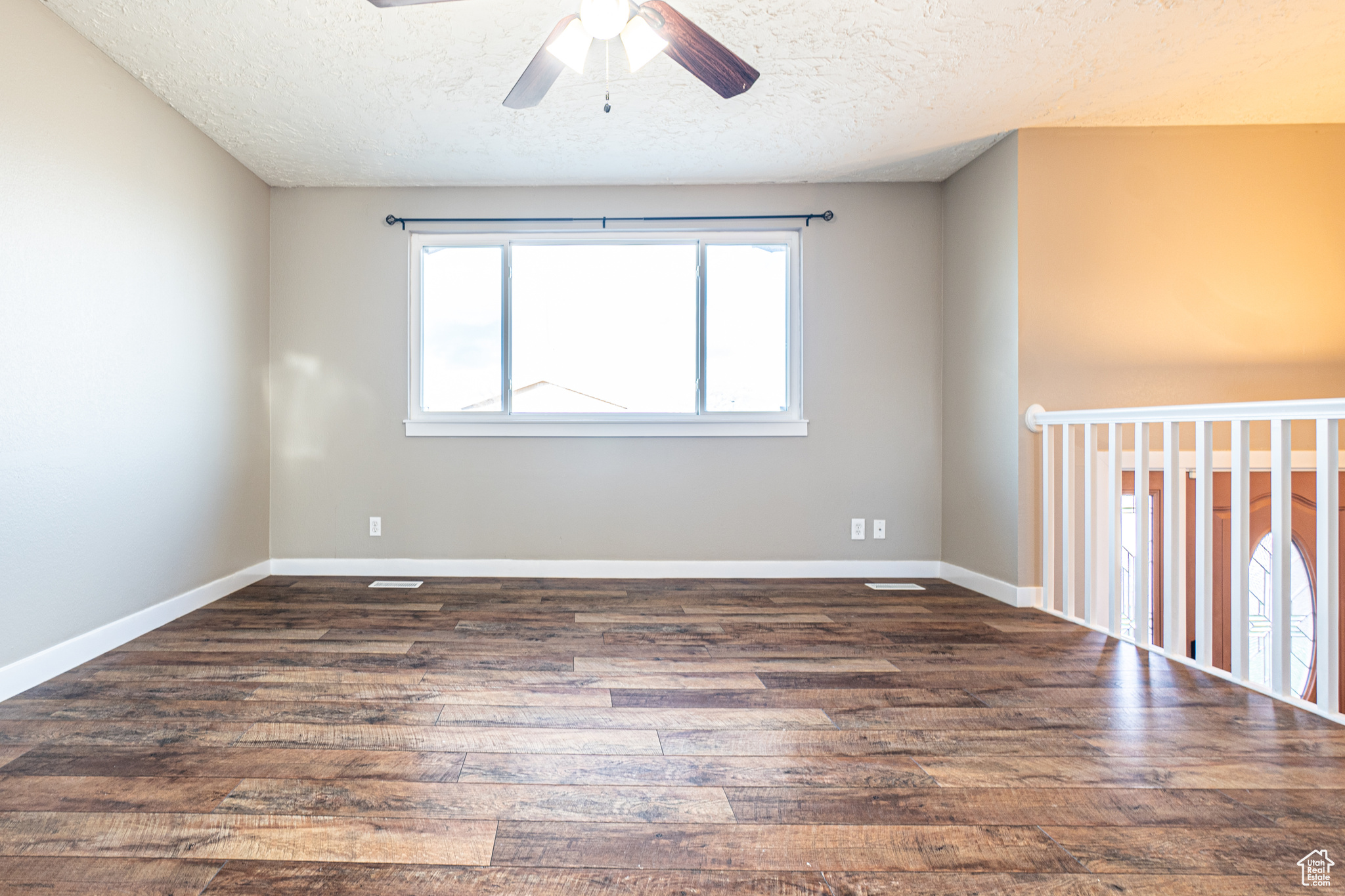 Spare room featuring ceiling fan, dark wood-type flooring, and a textured ceiling