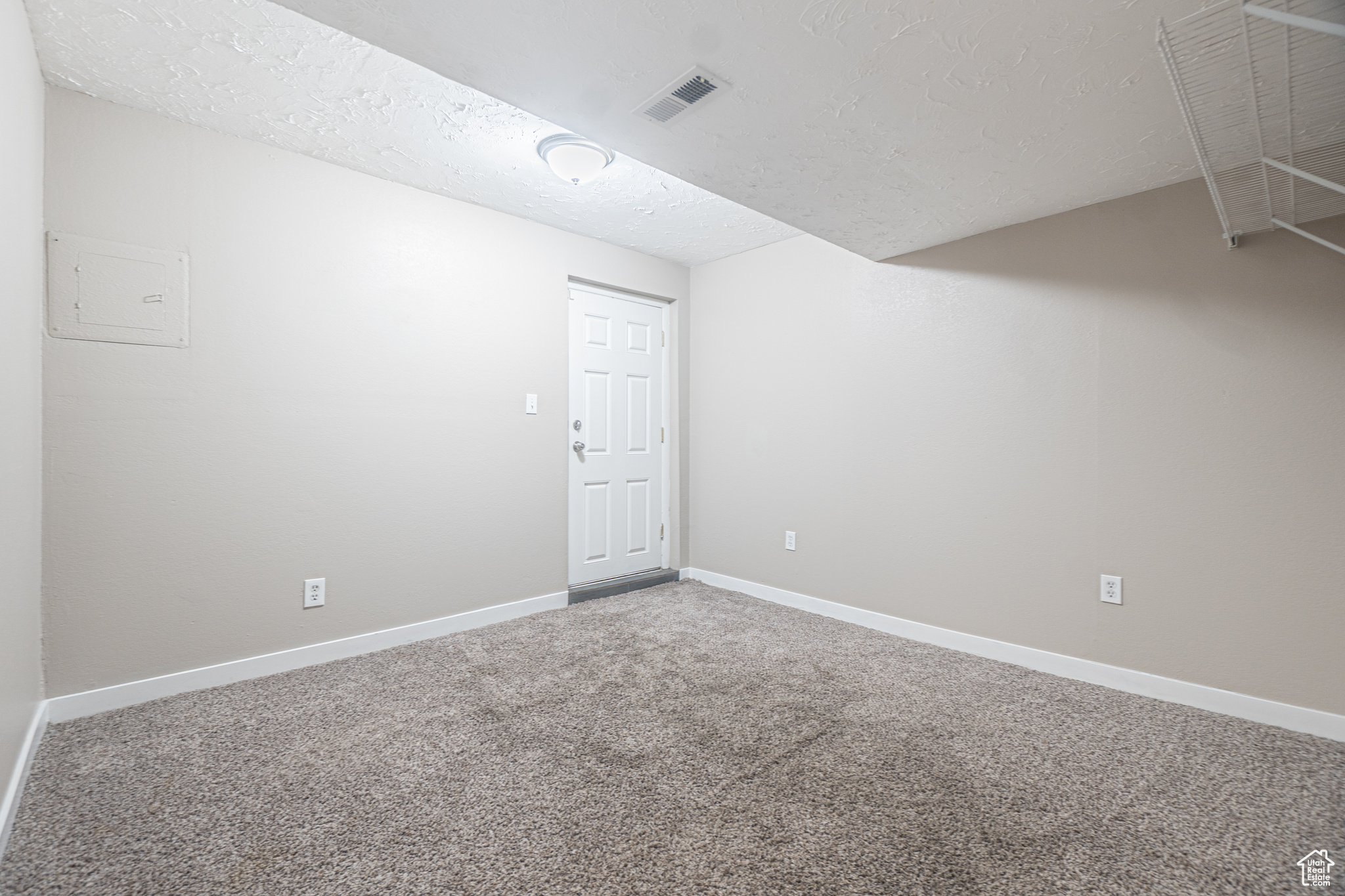 Empty room featuring carpet flooring and a textured ceiling