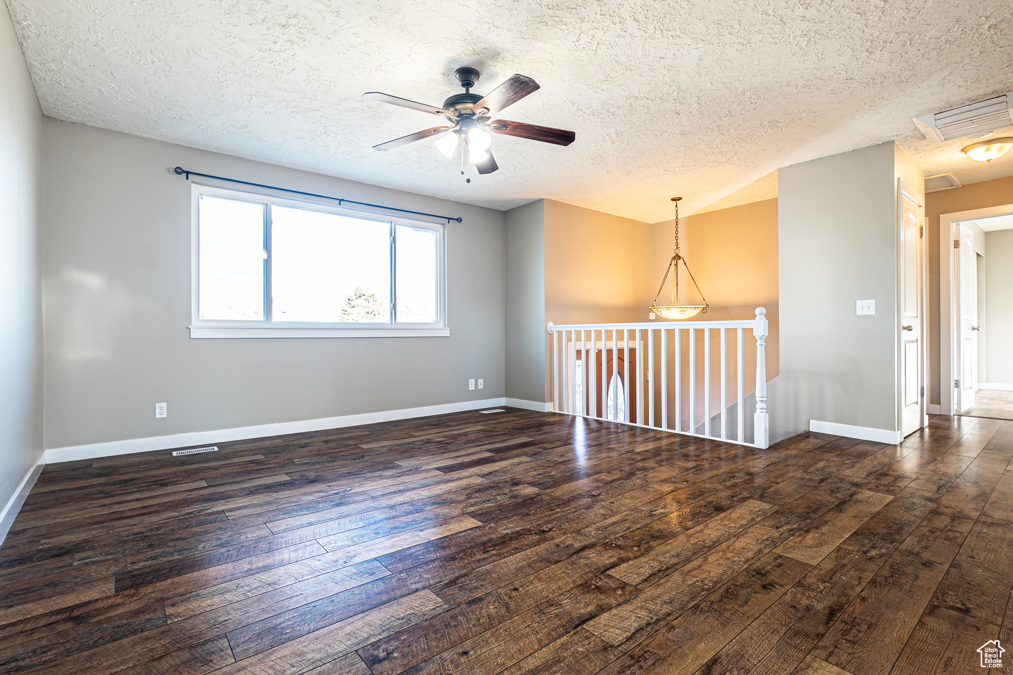 Unfurnished room featuring a textured ceiling, dark hardwood / wood-style floors, and ceiling fan